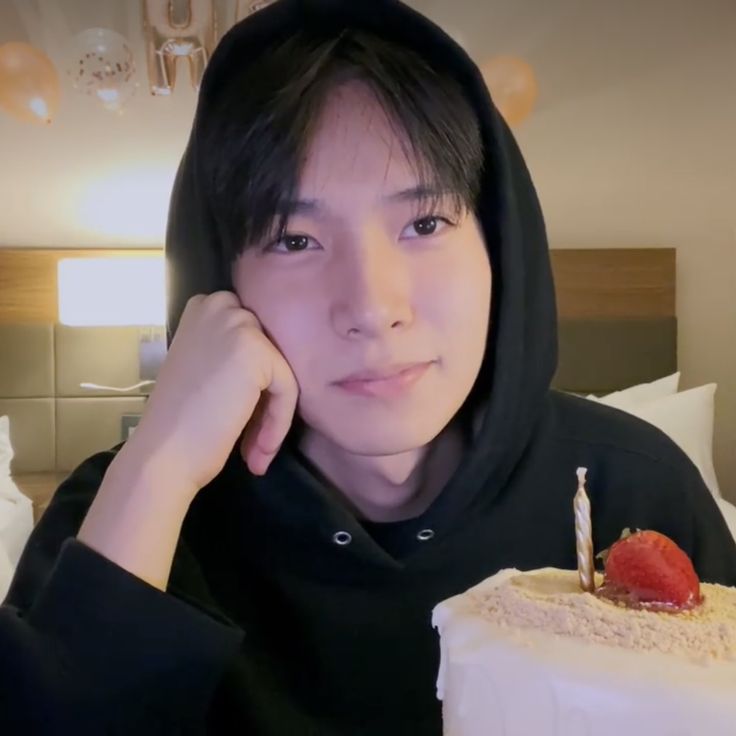 a young man sitting in front of a cake with a candle on top of it