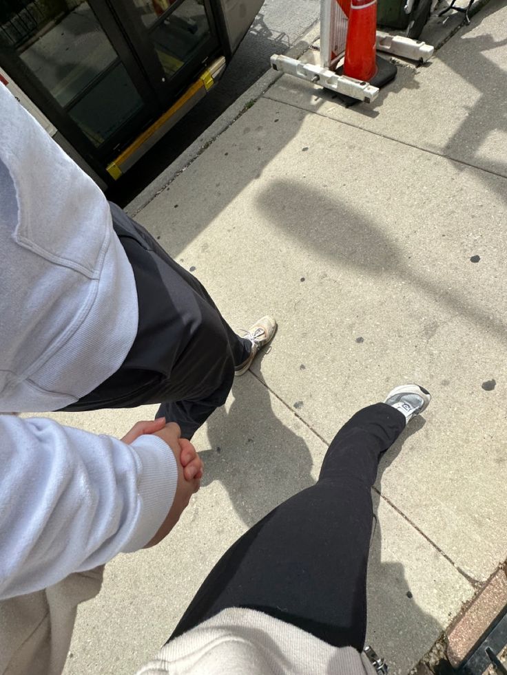 two people standing on the sidewalk with their feet in each other's pockets and holding hands