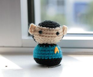 a small crocheted doll sitting in front of a window