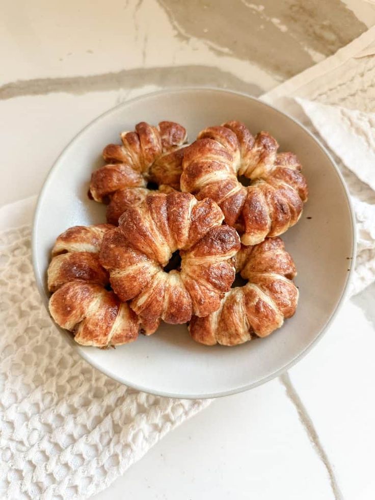 several croissants on a white plate sitting on a table