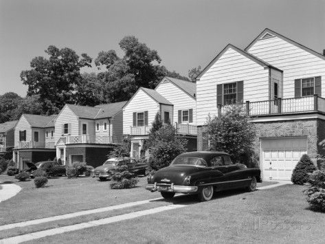 black and white photograph of cars parked in front of houses