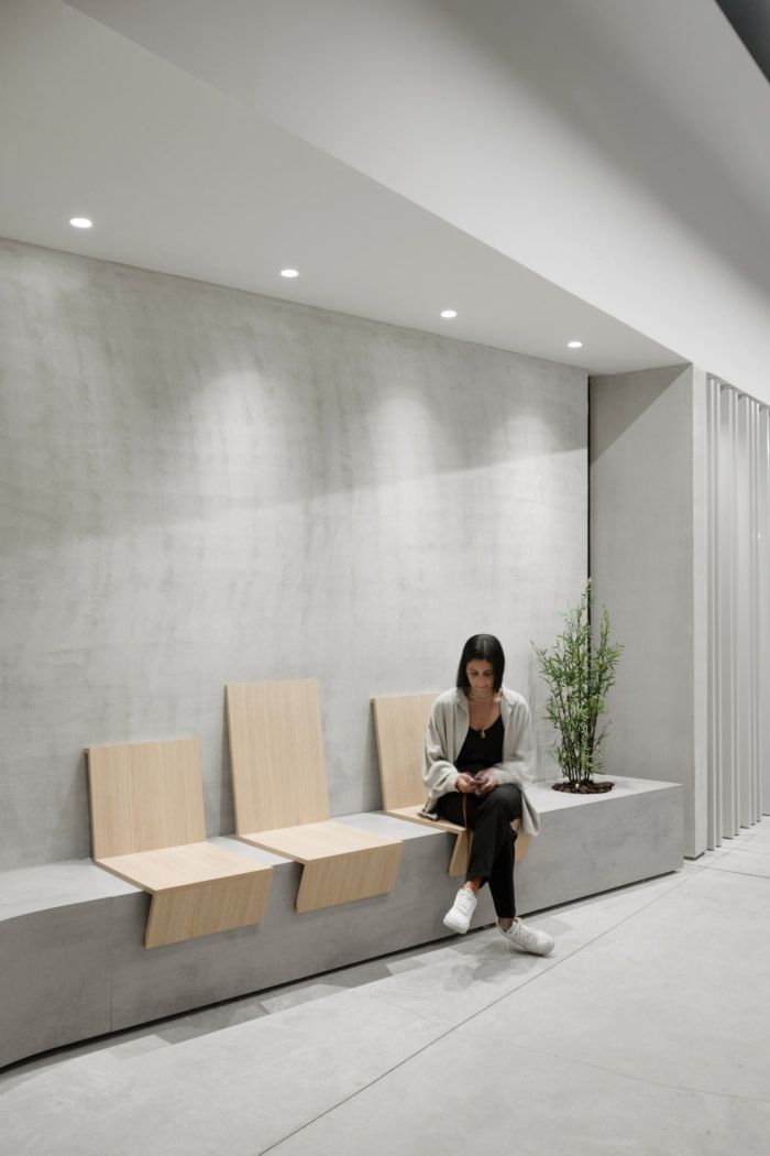 a woman sitting on top of a bench next to a plant in a white room