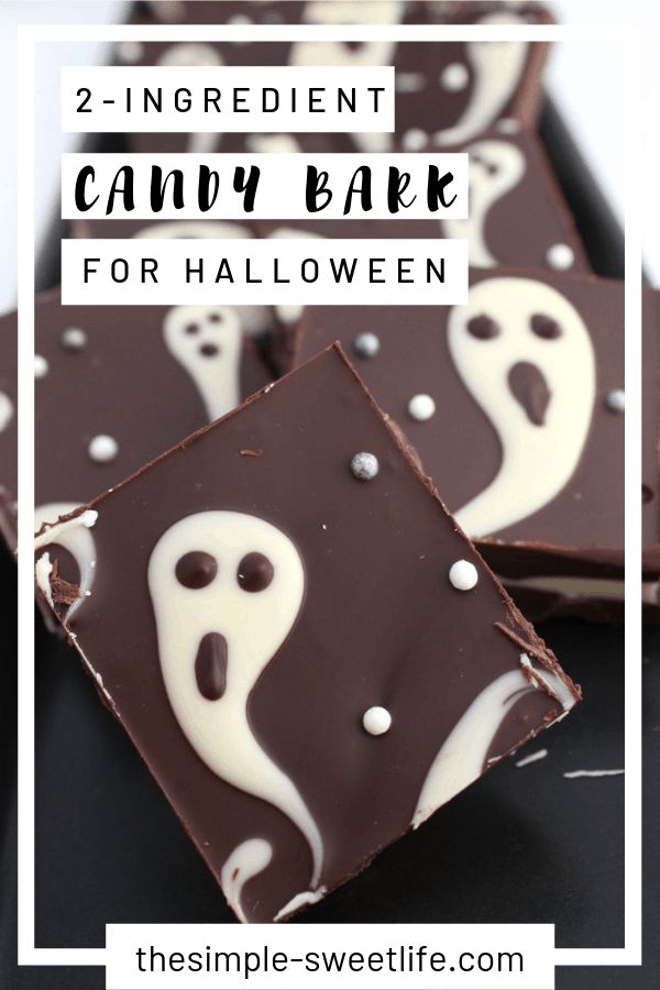 two ingredient candy bark for halloween with ghost faces and white icing on top, sitting on a black surface