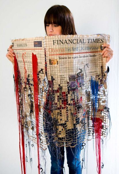 a woman is holding up a newspaper covered in strings