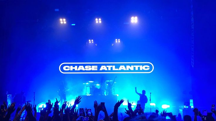 the stage at chase atlantic is lit up with blue lights and hands in the air