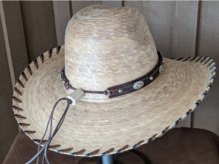 Brown leather has been trimmed with imprinted brown leather and accented with sunburst sliders and shiny nailspots. The hatband has brown leather lace and an antler bead that slides the hatband securely around the crown of your hat. It is 23" long and 20mm wide. Hat not included. Custom Adjustable Brown Hat Bands, Adjustable Brown Hat Band For Flat Crown, Adjustable Brown Country Style Hat Bands, Adjustable Handmade Leather Hat Bands, Distressed Brown Adjustable Hat For Western-themed Events, Custom Brown Hat Bands For Ranch, Brown High Crown Country Hat, High Crown Brown Country Hat, Adjustable Distressed Brown Hats For Rodeo