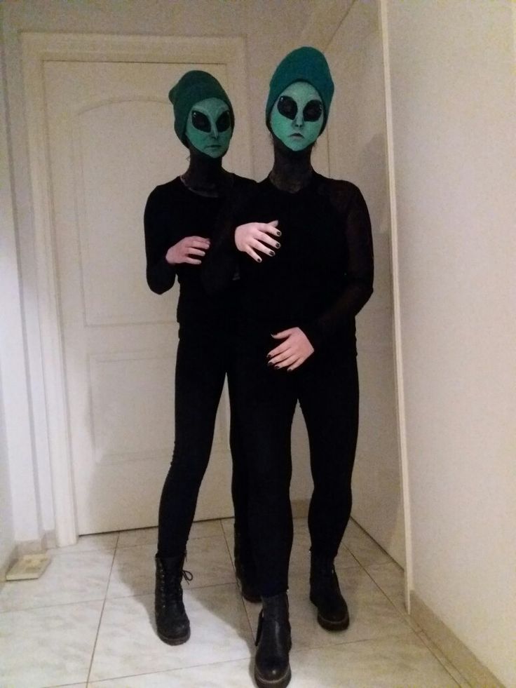 two people in alien costumes standing next to each other on a tile floor with white walls