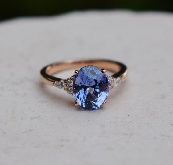 a tan and blue ring sitting on top of a white stone surface with diamonds around it