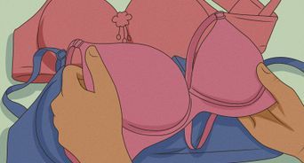 a hand holding a pink bra over a blue bag with other bras on it