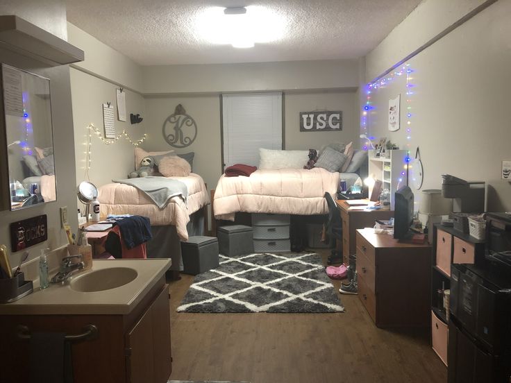 two beds in a dorm room with lights on the ceiling and other items scattered around