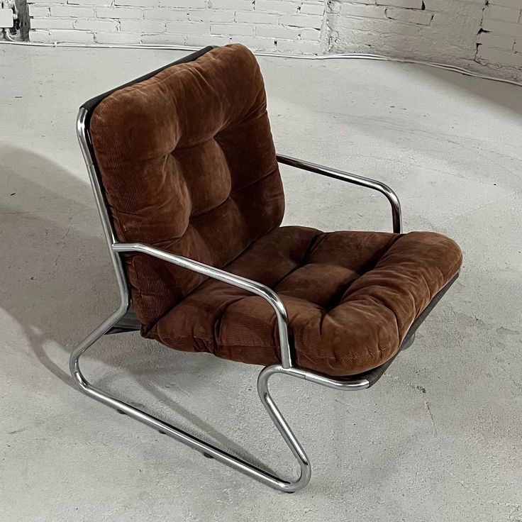 a brown chair sitting on top of a white floor next to a brick wall and metal frame