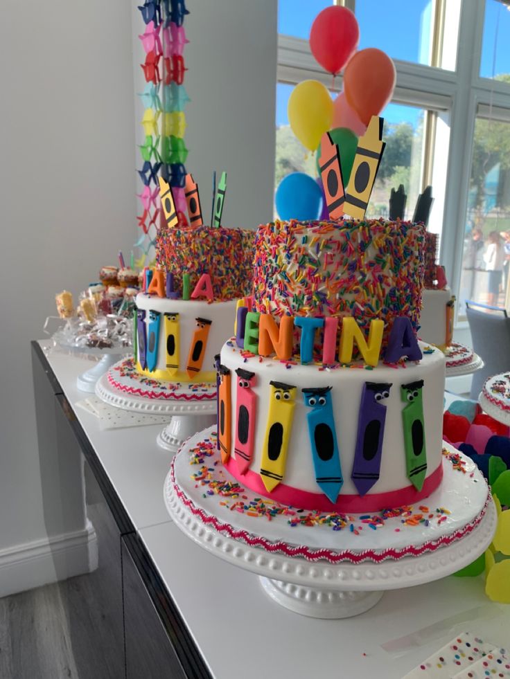 two birthday cakes with balloons and confetti on top