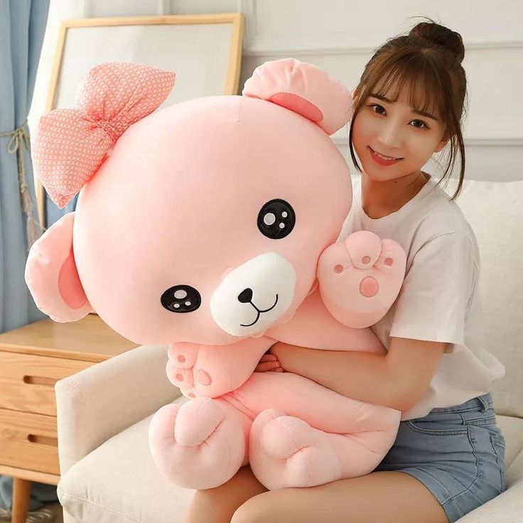 a woman holding a large pink teddy bear