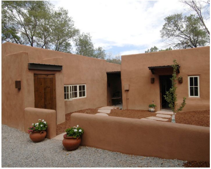 a adobe style house with two potted plants in front