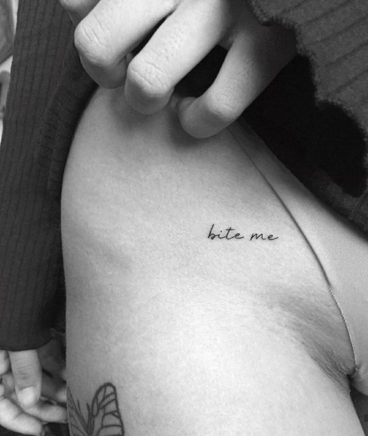 a woman's stomach with the words bite me tattooed on her left side ribcage