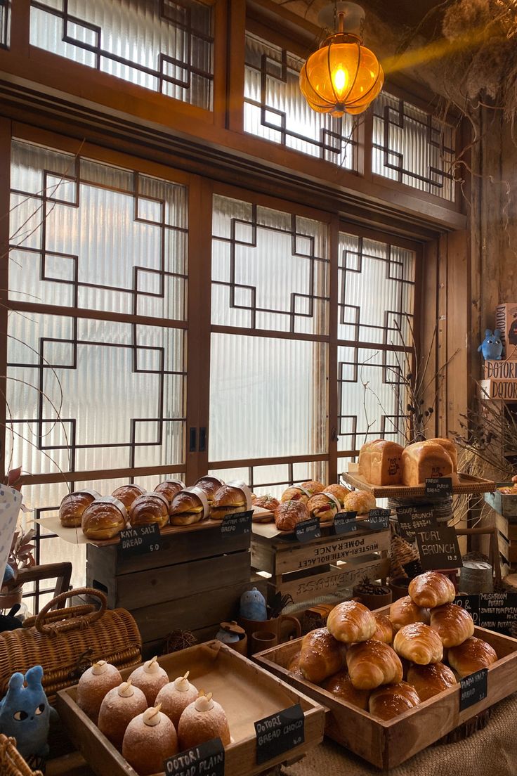 breads and pastries are on display in front of large windows