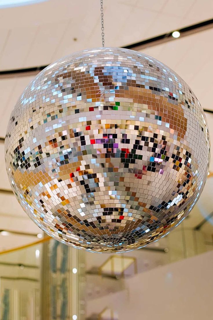 a disco ball hanging from the ceiling in a building with multiple colors and shapes on it