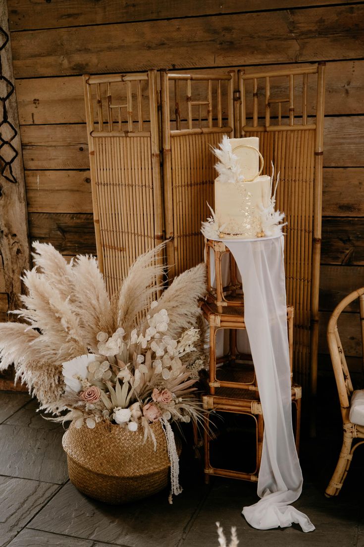 a tall white cake sitting on top of a table next to a basket filled with flowers