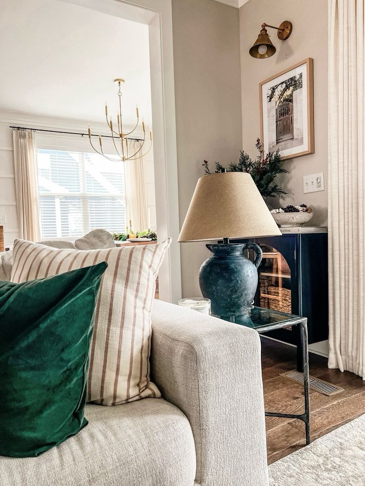 a living room filled with furniture and a lamp on top of a coffee table in front of a window