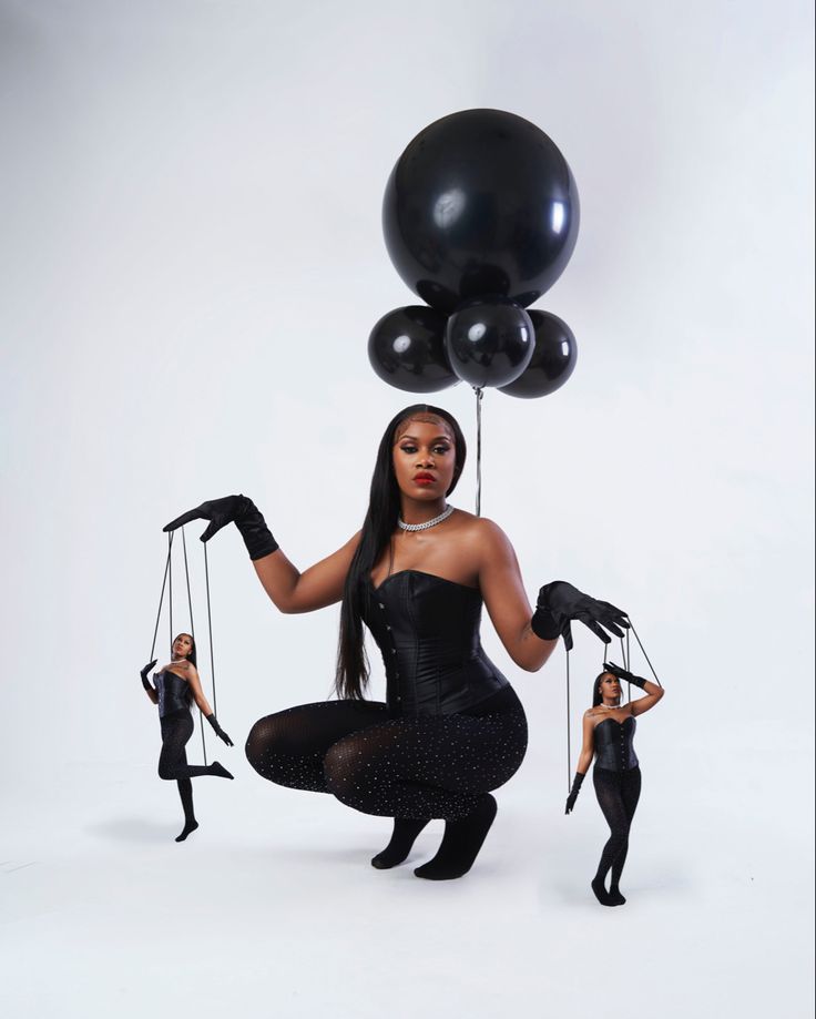 a woman in tights and heels holding black balloons while another woman stands behind her