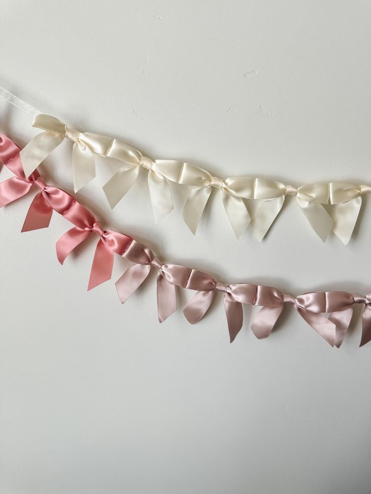 some pink and white bows are hanging on the wall