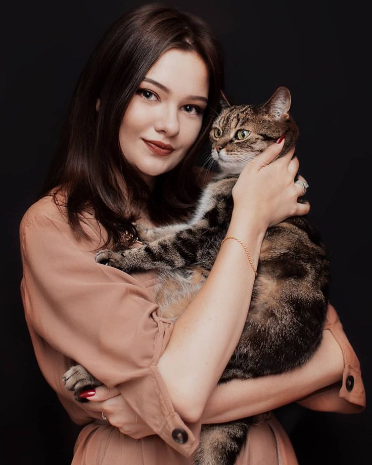 a woman holding a cat in her arms and looking at the camera with an intense look on her face