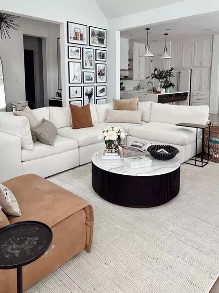 a living room filled with white furniture and pictures on the wall above it's coffee table