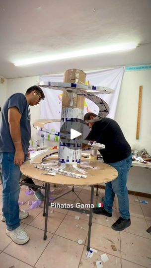 two men are working on a model in a room with white walls and tile flooring