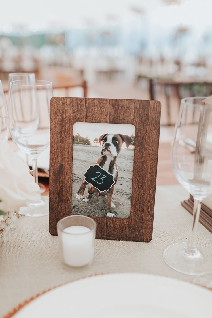 a wooden frame sitting on top of a table next to wine glasses and a candle