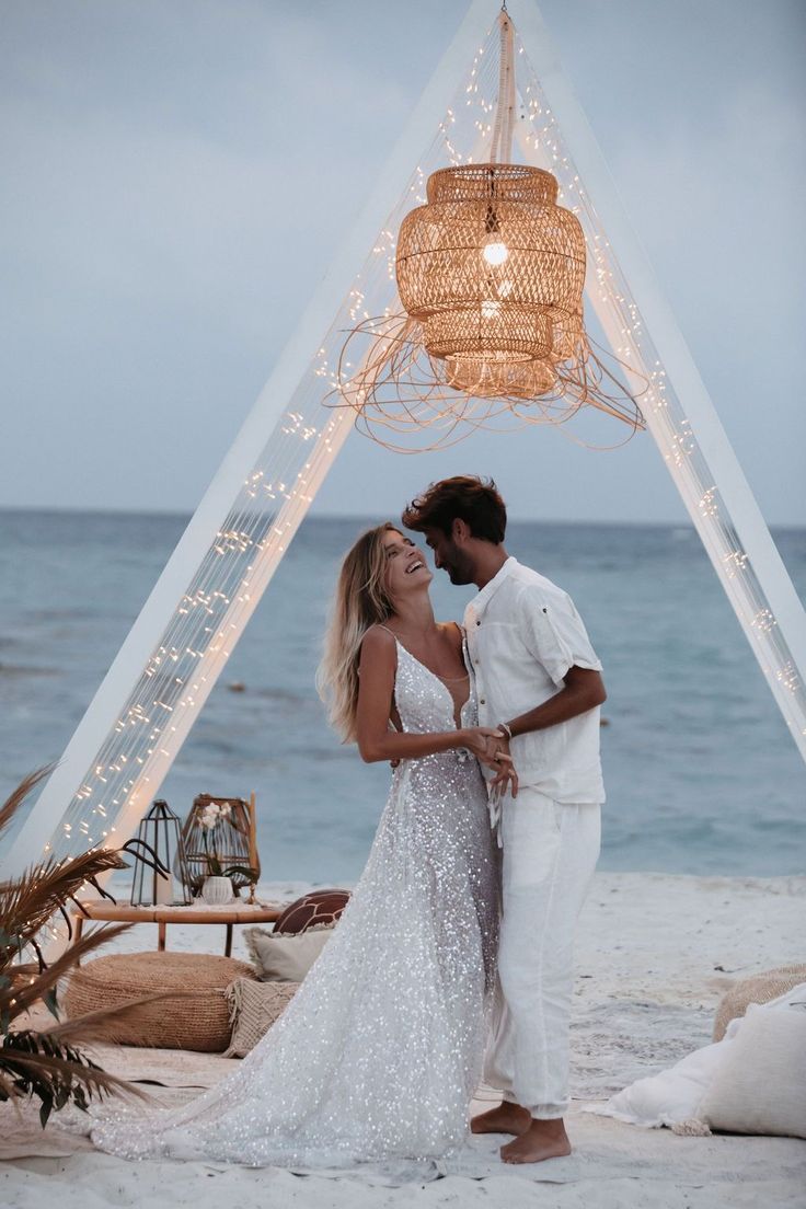 a man and woman are standing under a gazebo on the beach at night time