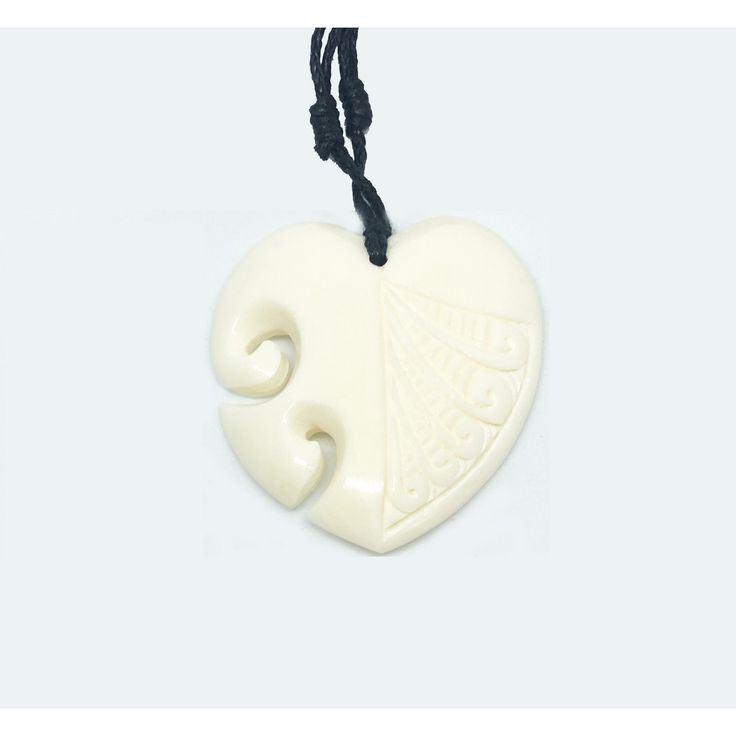 a white ceramic heart shaped pendant on a black cord