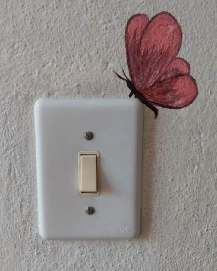 a white light switch with a red butterfly on it's back side and a pink flower attached to the wall