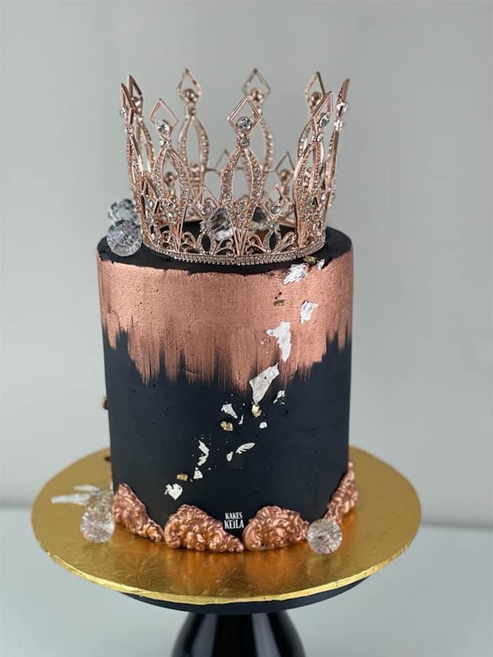 there is a black and gold cake with a crown on top that has some diamonds on it