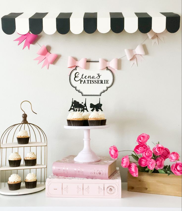 cupcakes are sitting on top of a cake stand with pink flowers in the foreground