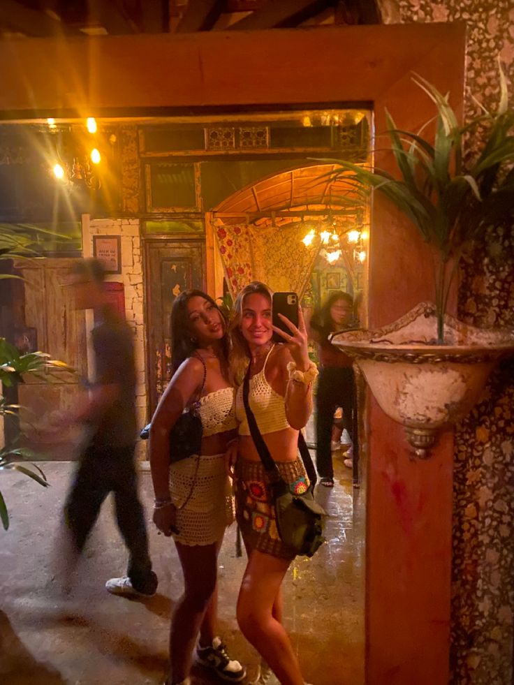 two women standing in front of a mirror taking a selfie