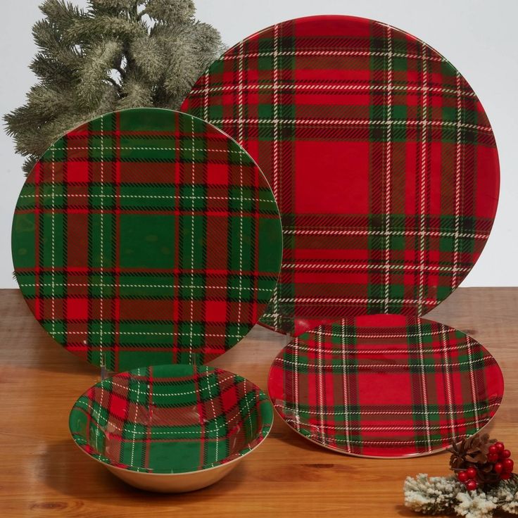 two plates with plaid designs on them sitting next to a christmas tree and pine cones