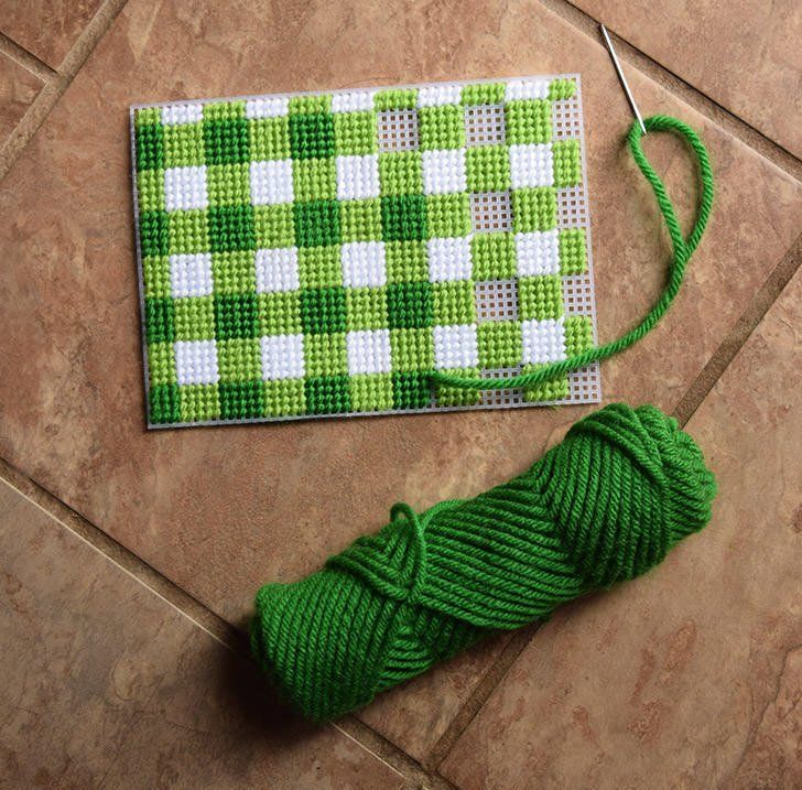 a green and white checkered table cloth next to a spool of thread on the floor