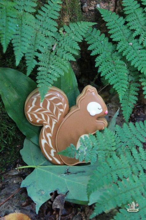 a brown and white toy squirrel sitting on top of a green leafy forest floor