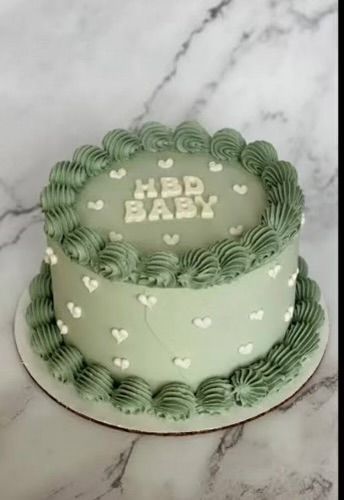 a green and white baby cake on a marble counter top with the words happy baby written in frosting