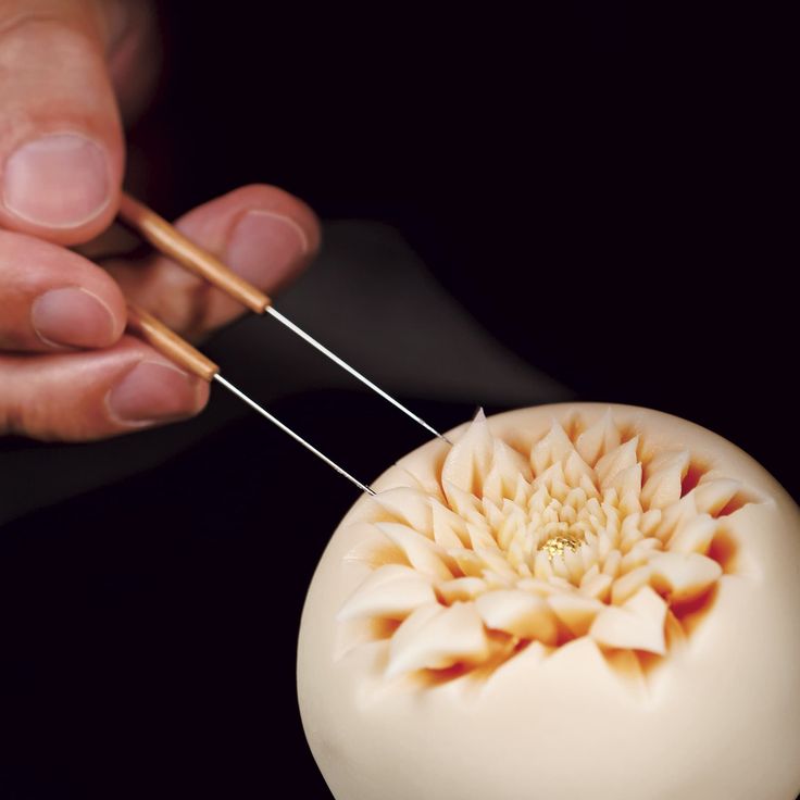 a person is using needles to thread the top of a white object with flowers on it