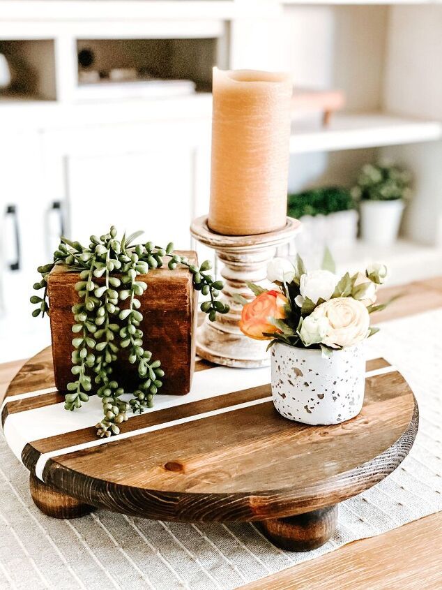 a wooden table topped with potted plants next to a candle on top of it