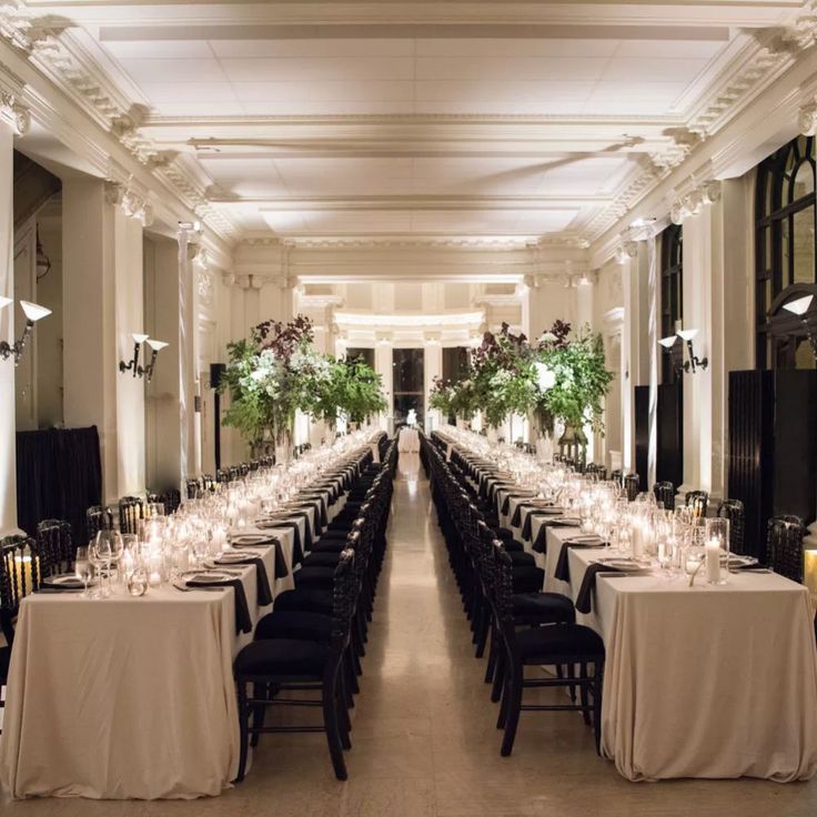 a long dining hall with tables and chairs set up for an event or function in the evening