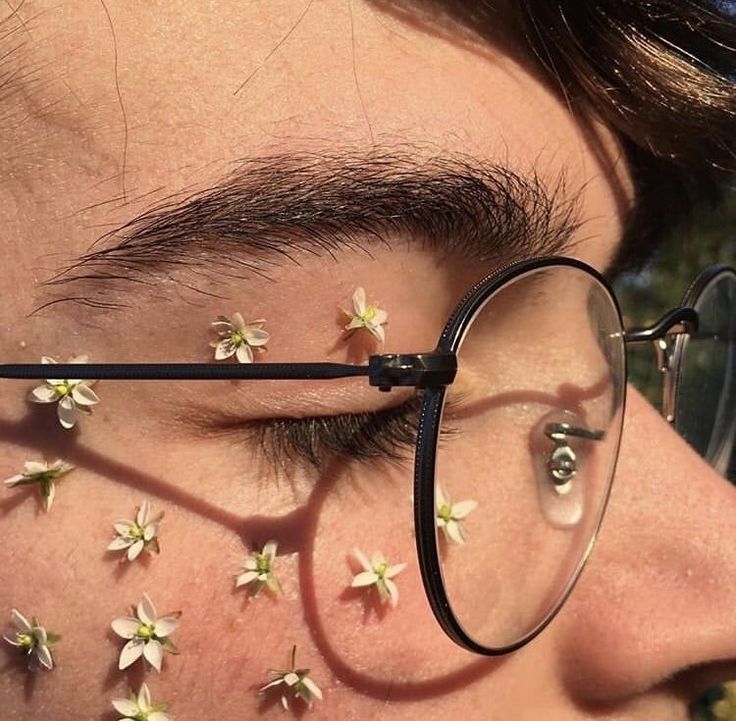 a close up of a person wearing glasses with flowers on the side of their face