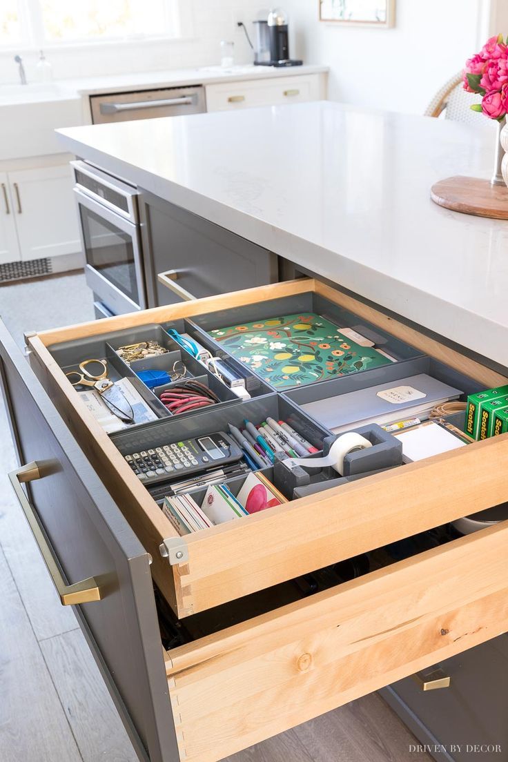 an open drawer in the middle of a kitchen counter with drawers on both sides and other items inside