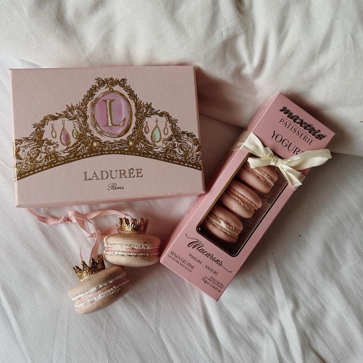 an open box of macaroons sitting on top of a bed next to other items