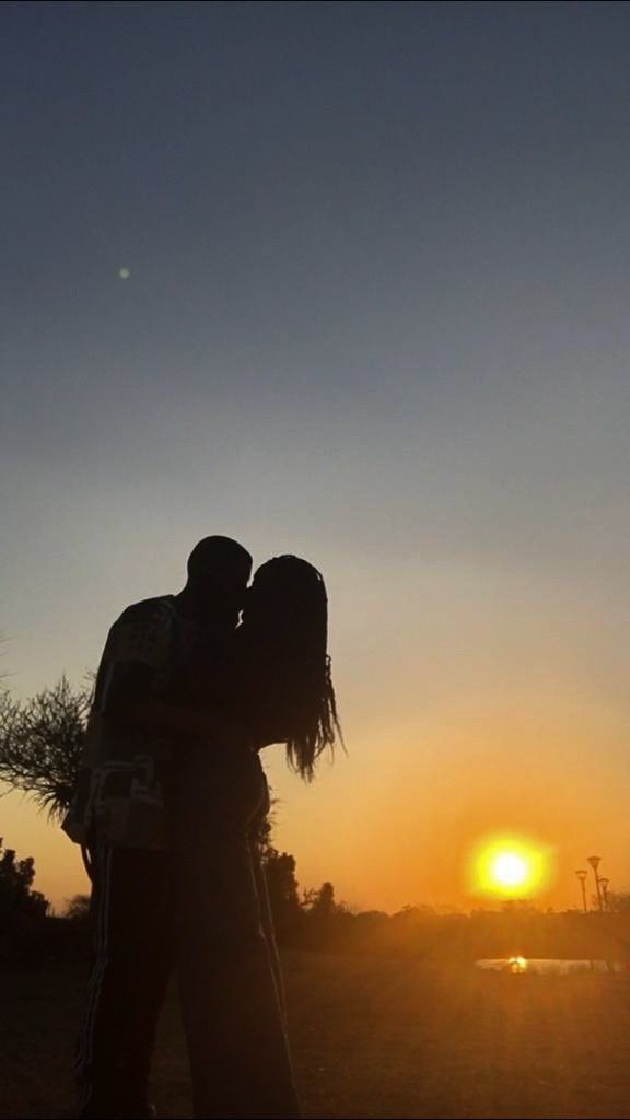 two people are kissing in front of the sun