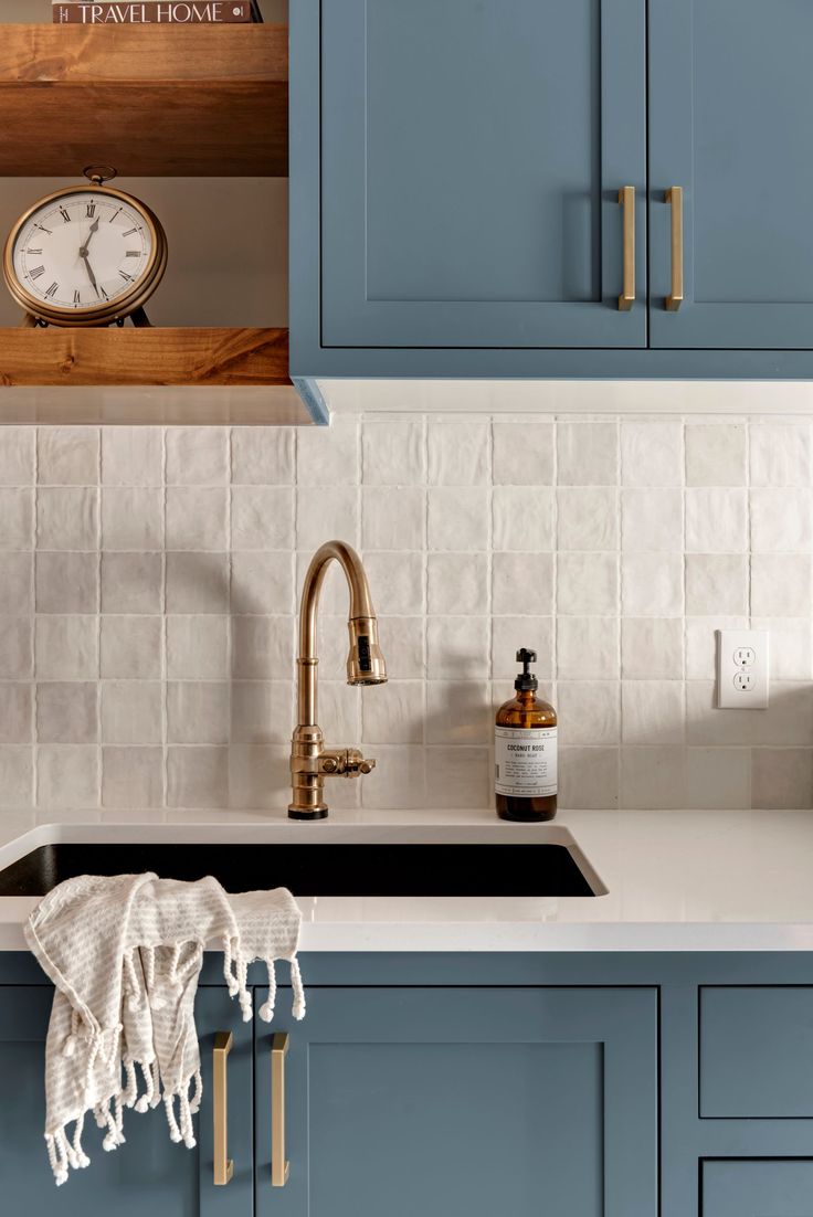 a kitchen with blue cabinets and a white clock on the wall above the dishwasher