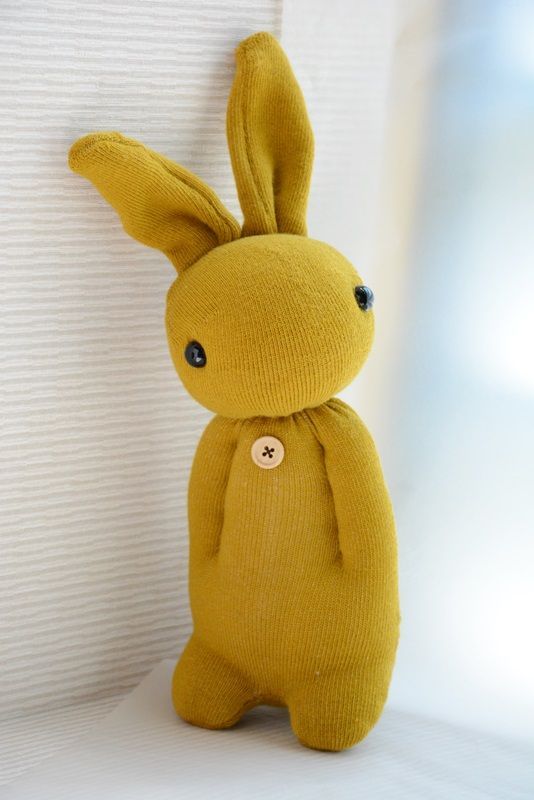 a yellow stuffed animal sitting on top of a white bed next to a wall and window