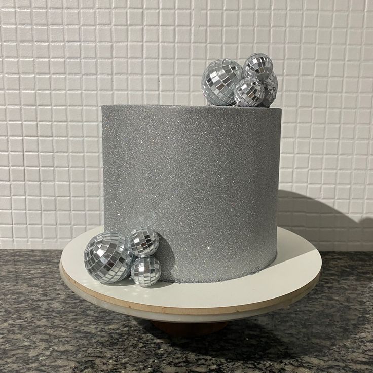 there is a silver cake with three shiny balls on the top and two smaller ones in the middle