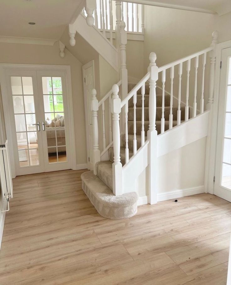 an empty living room with stairs leading up to the second floor and french doors on both sides